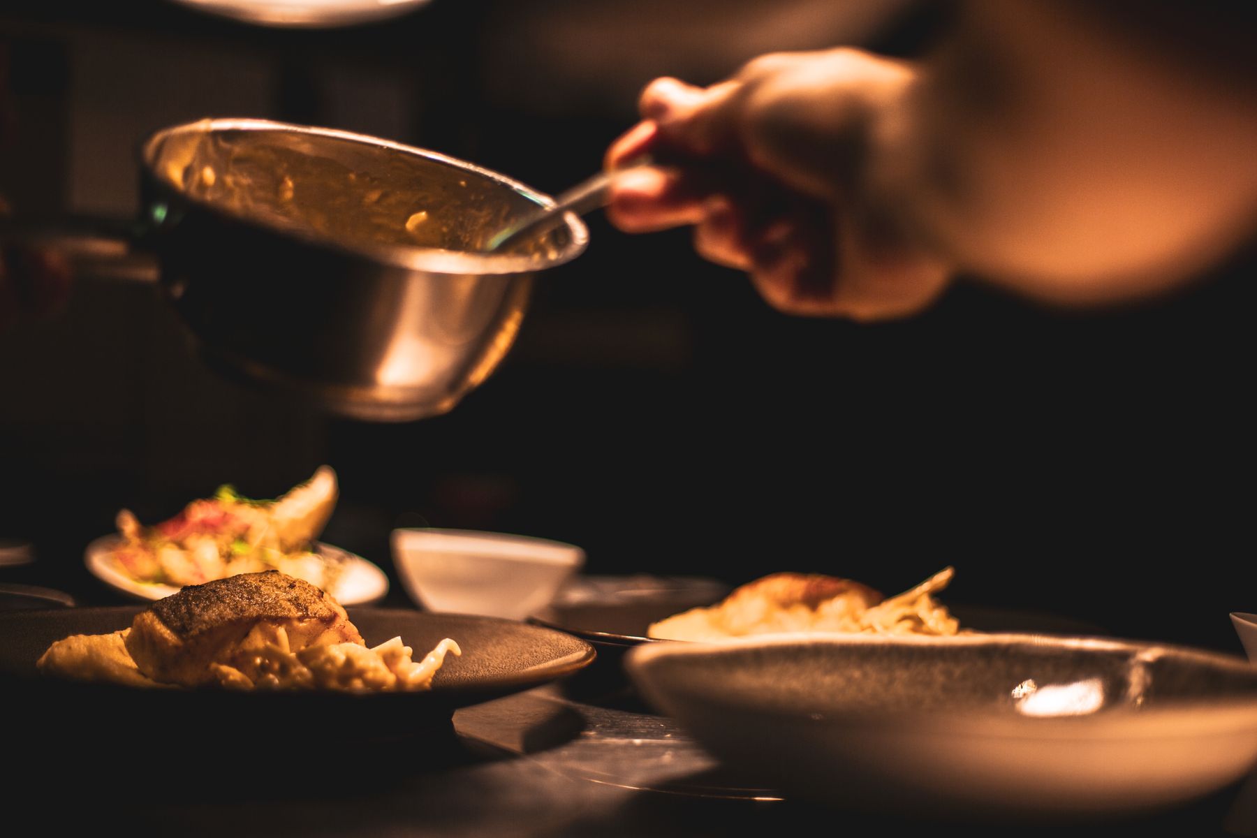 A cook presents a bowl of food at the pass